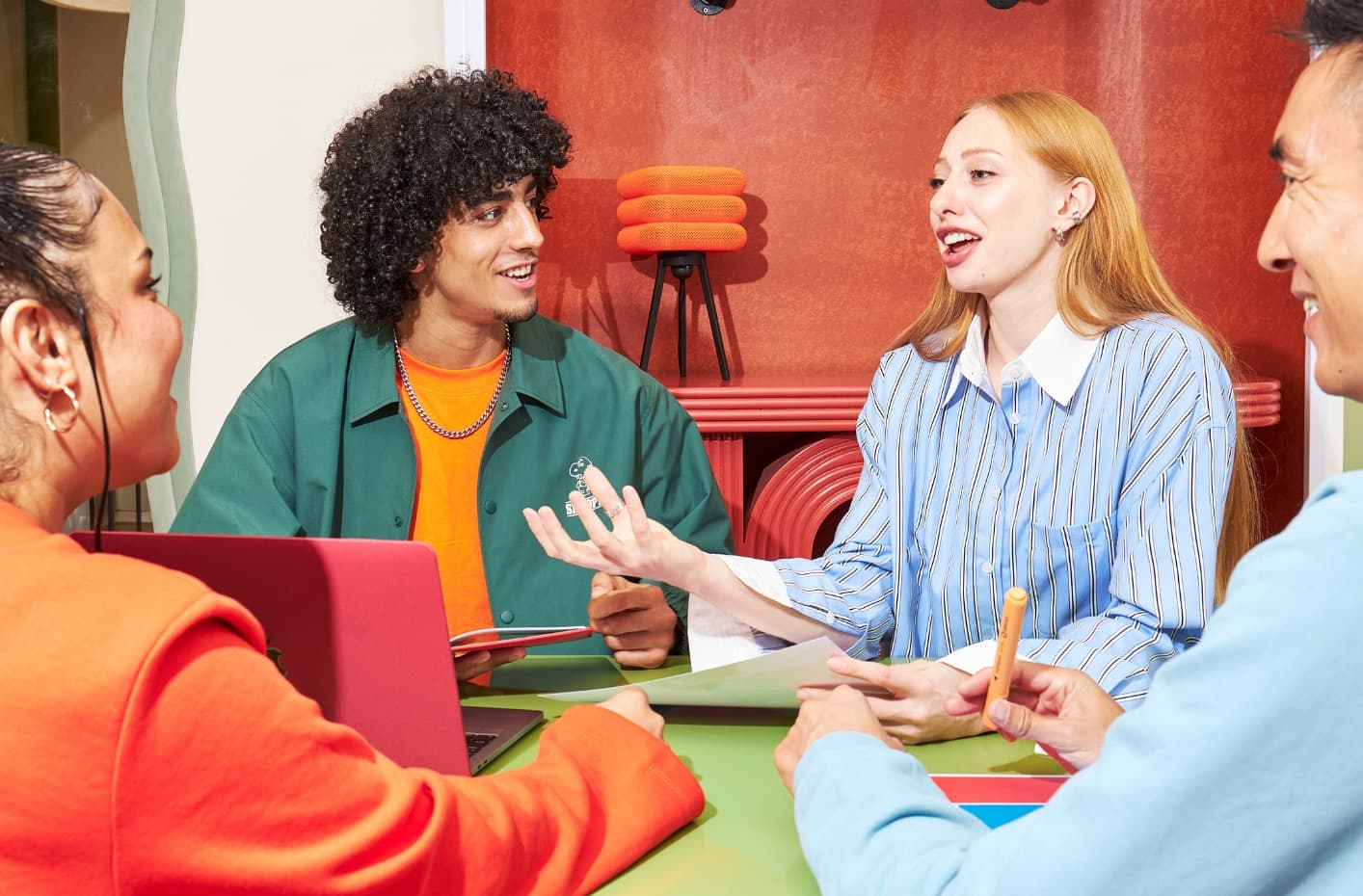 A team around a table, one person speaking while the others listen